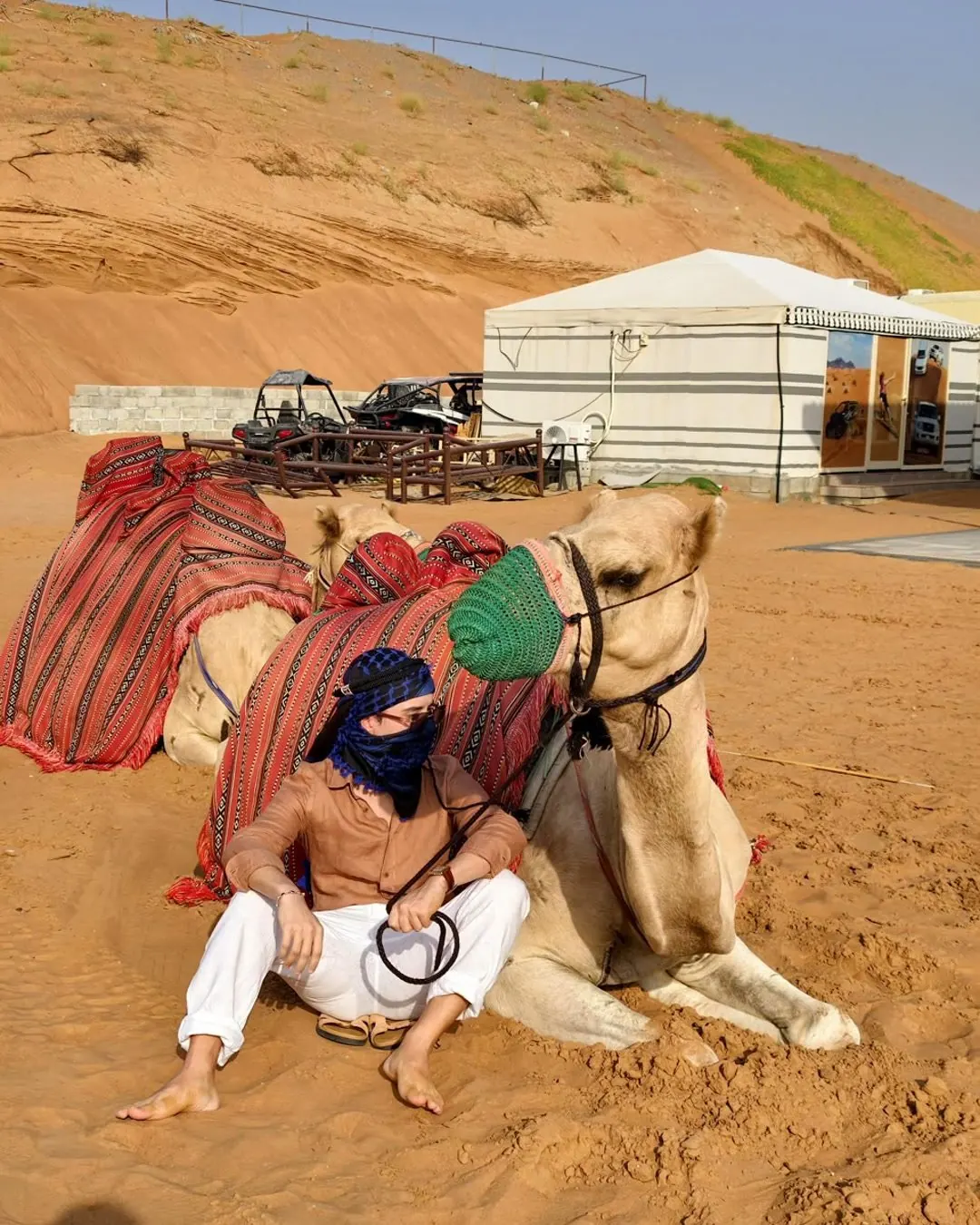 Guest sitting with a camel at the desert camp