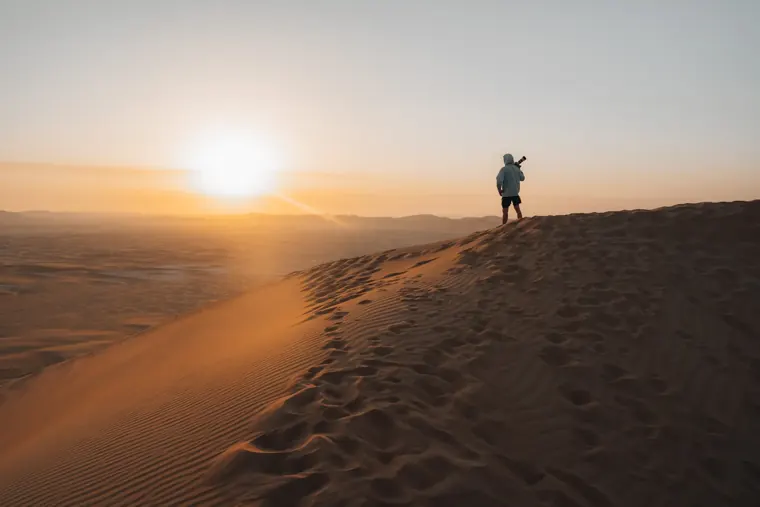 Guest on a dune ridge at sunset during a VIP desert safari with quad bike in Dubai